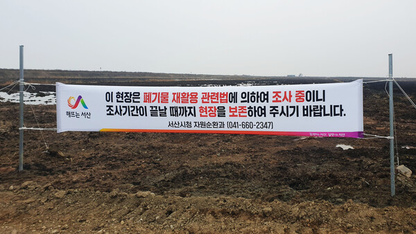 현장 조사를 위해 서산시청 공무원이 부숙토가 뿌려진 농지에 현수막을 게시했다